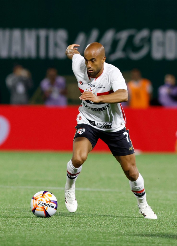 Jogador em campo correndo em direção à bola durante uma partida de futebol.