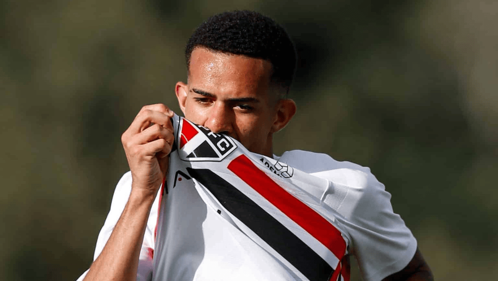 Parcelamento de R$ 1 milhão em 3x do São Paulo em novo acordo por joia 1 Jogador masculino segurando e beijando a camisa do time de futebol São Paulo FC durante um treino.