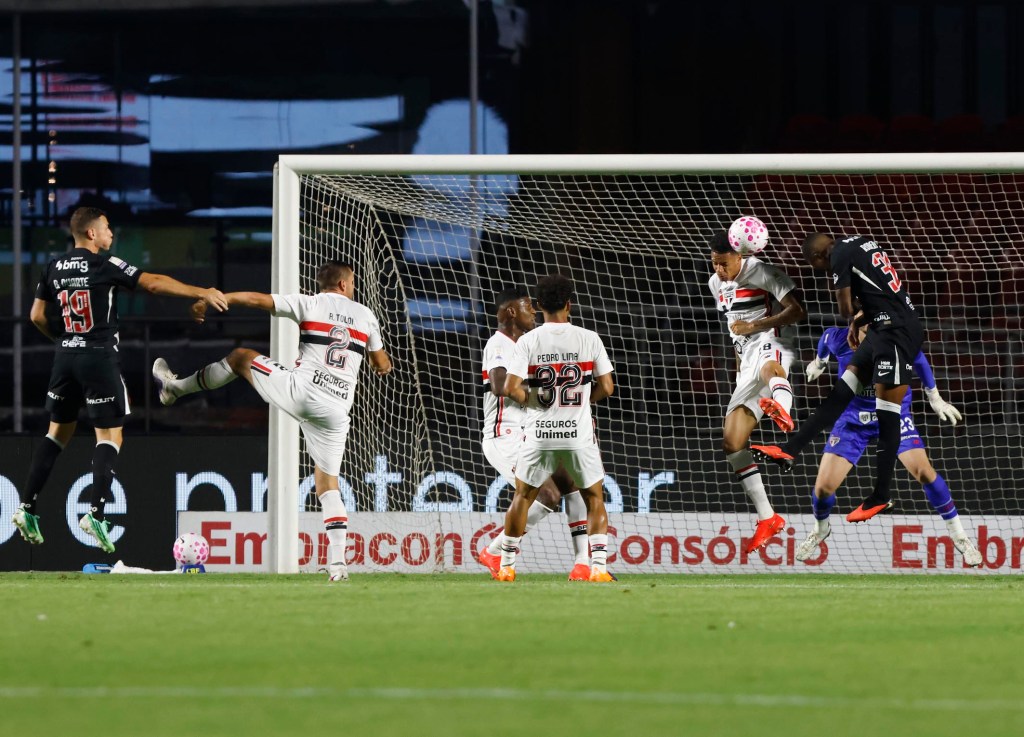 Libertadores já entra no discurso de técnico do São Paulo 1 Jogadores de futebol em ação durante um jogo, um deles chutando a bola em direção ao gol enquanto os defensores tentam bloquear o chute.